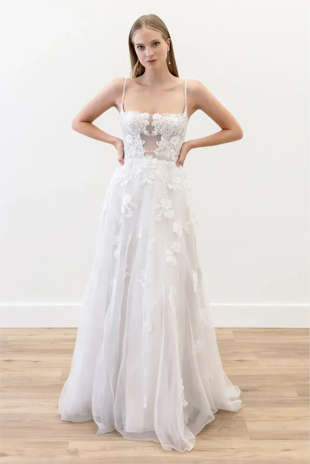 White wedding dress with floral details on a wooden floor