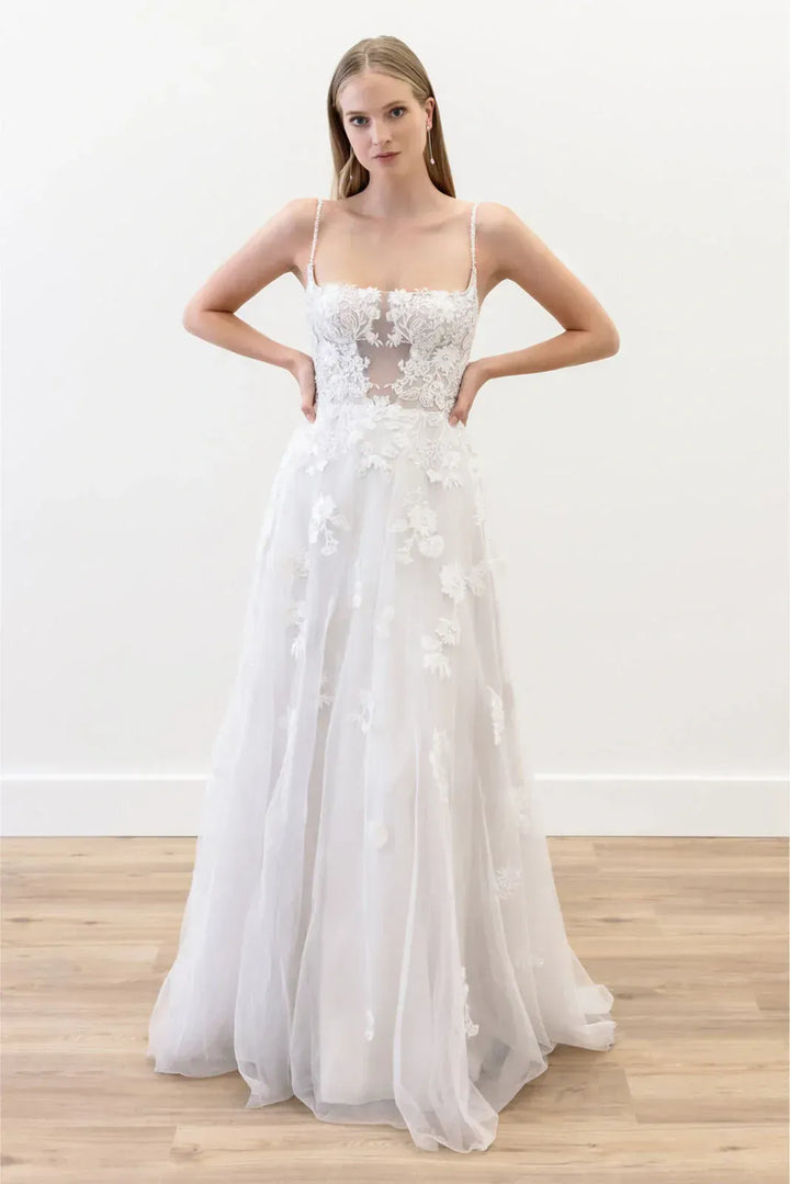 White wedding dress with floral details on a wooden floor
