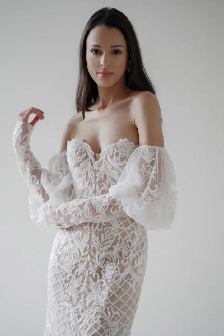 Woman wearing a white lace dress against a plain background