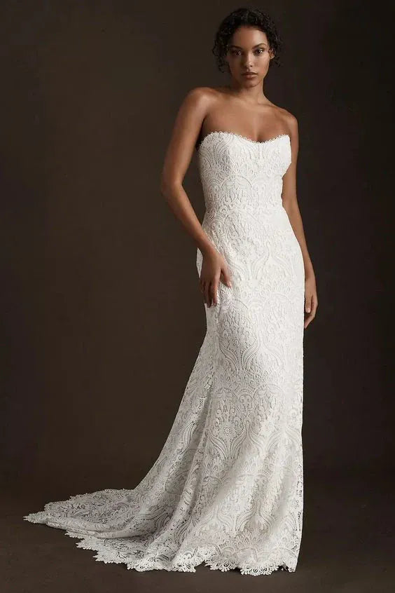 Woman wearing a strapless lace wedding dress against a dark background