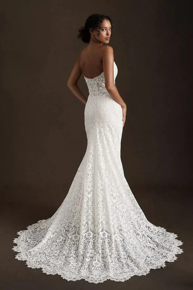 Model wearing a white lace wedding dress against a dark background