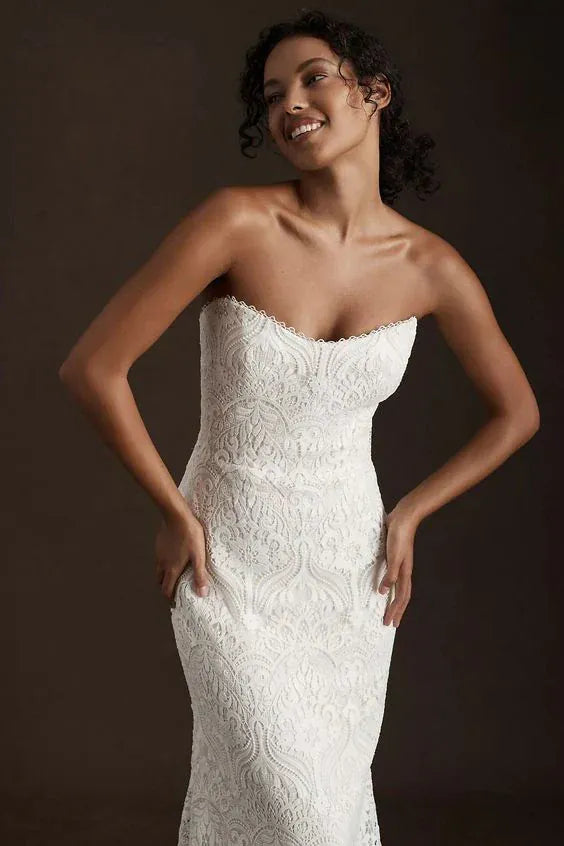 Woman wearing a white strapless wedding dress against a dark background