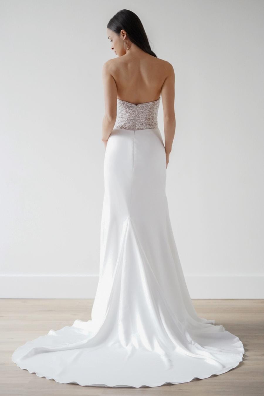 White wedding dress with a beaded bodice on a plain background