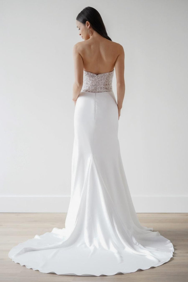 White wedding dress with a beaded bodice on a plain background