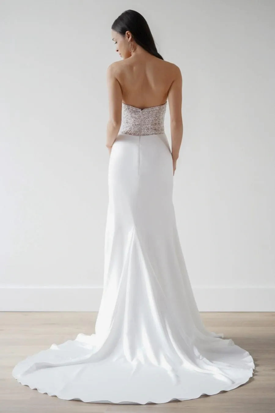 White wedding dress with a beaded bodice on a plain background