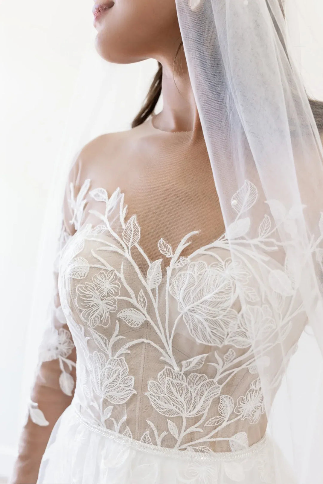 Close up of Locket by Watters Esme white tulle A-line gown with floral motifs and long sleeves