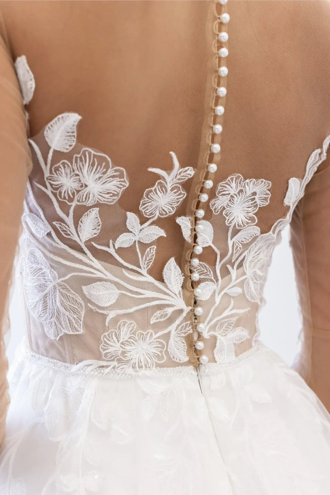 Close up of Locket by Watters Esme ivory tulle A-Line gown with illusion floral bodice and pearl buttons