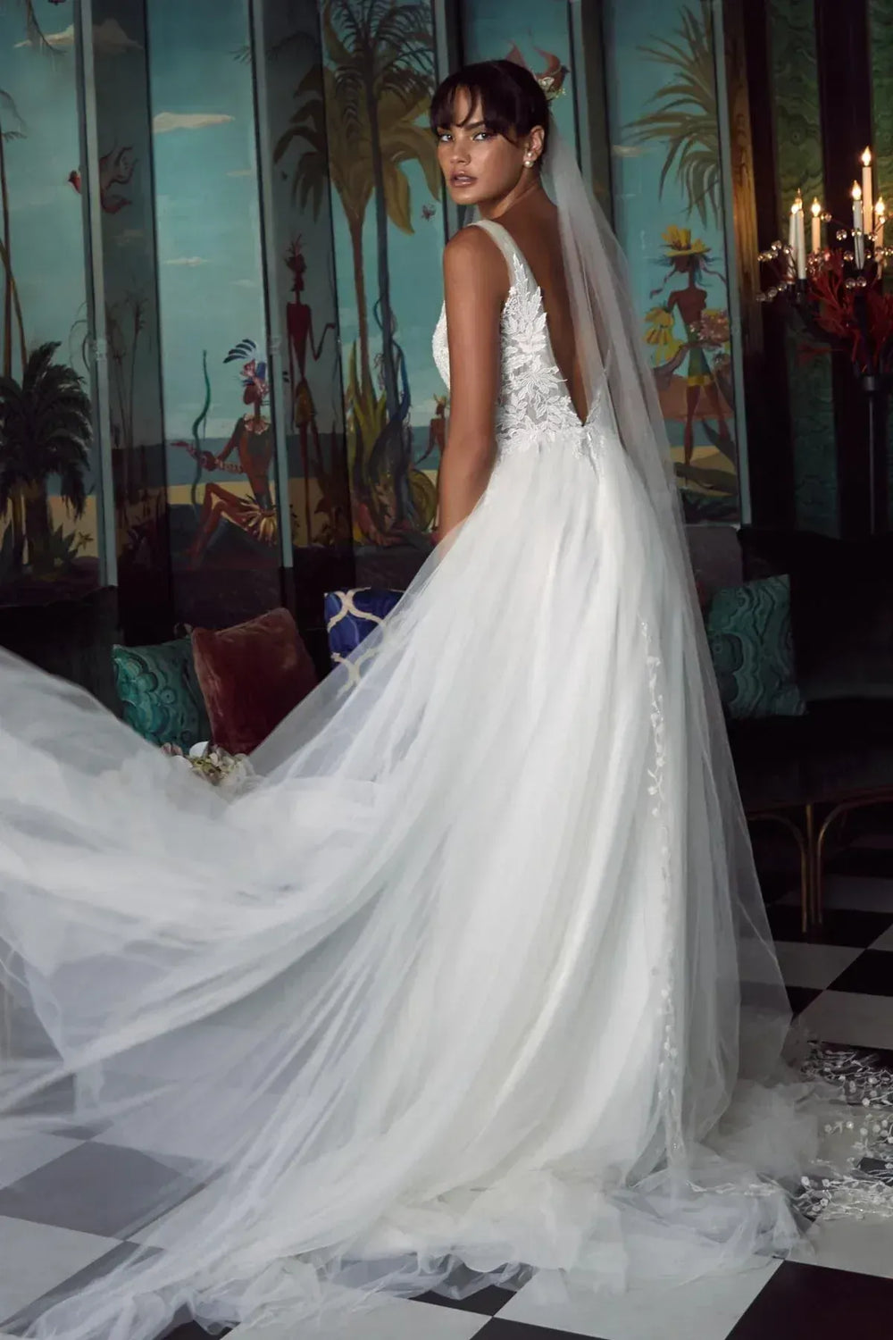 Woman in a white wedding dress with a long train in a decorated room.
