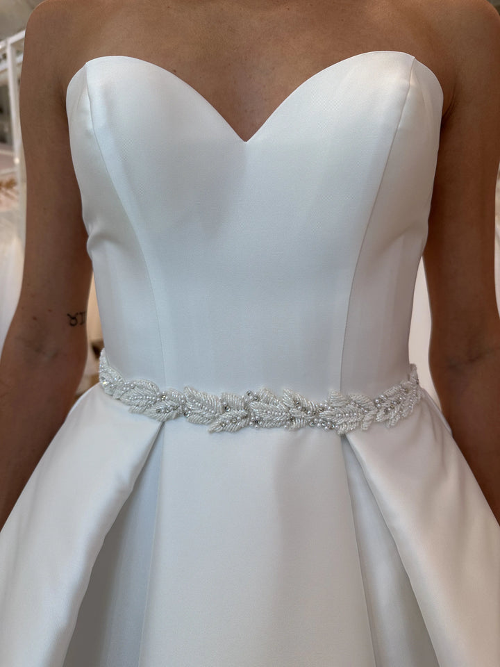 Close up of Luxe Privée Sierra Belt ivory beaded leafy belt on satin A line silhouette with strapless bodice and pleated skirt